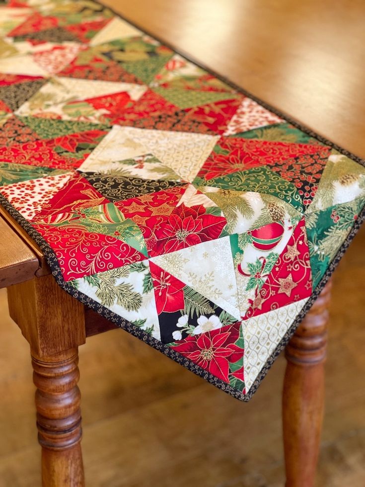 a wooden table with a red and green patchwork quilt on it's edge