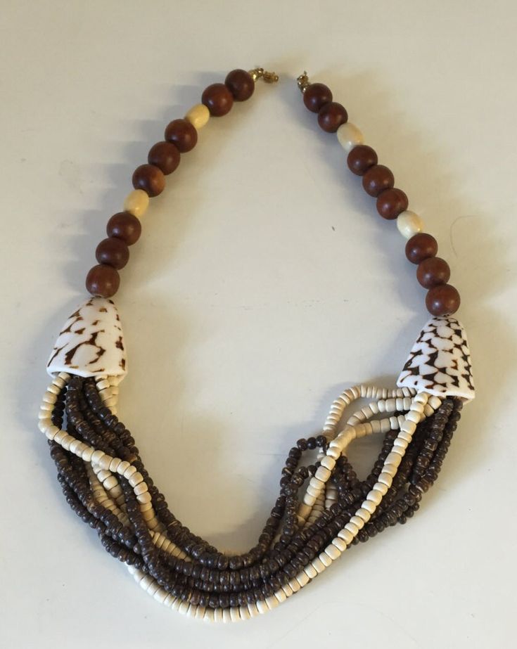 "This necklace has a beautiful carefree beach vibe! Pook a shell and wooden beads with two larger seashell beads on either side. What a great 1980's vintage summer staple.  This is a vintage used item and is in great vintage used condition with little to no wear, there are no missing or broken beads,  It is approximately 22\" in length." Adjustable Multi-strand Shell Necklace For Beach, Beach Necklace With Brown Round Beads, Vintage Brown Necklaces For The Beach, Bohemian Multi-strand Shell Necklace For Beach, Vintage Brown Jewelry For The Beach, Vintage Brown Beaded Necklaces For Beach, Wooden Bead Necklaces For Vacation, Handmade Multi-strand Shell Necklace For Beach, Beach Necklaces With Colorful Beads In Brown