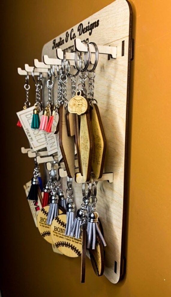 a bunch of keys hanging from a hook on a wooden board with magnets attached to it