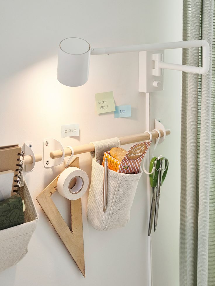 a white wall with some items hanging from it's hooks and a lamp next to it