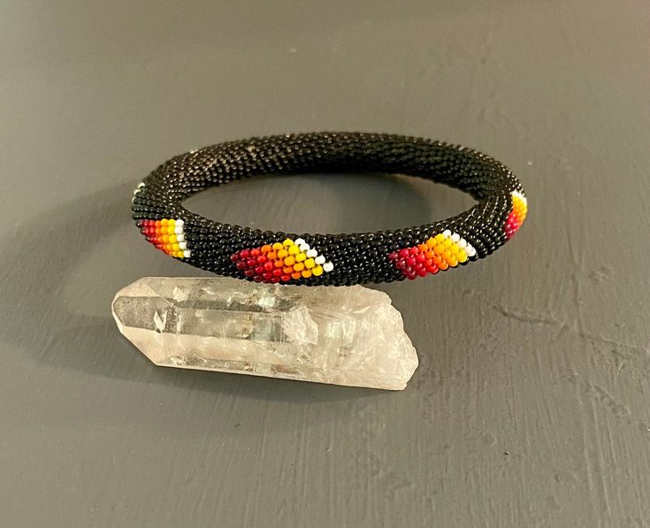 A Southwestern designed seed bead bangle black with oranges, reds and yellows Measures 2.5" across the inside of the bangles 7.50" measured on the mandrel Vintage Clothing & Jewelry with a Southwest Flair Check out my shop for more jewelry and clothing! https://www.etsy.com/shop/sierramadrevintage Festival Black Bracelets With Large Beads, Adjustable Black Cuff Bracelet With Colorful Beads, Black Bohemian Cuff Bracelet With Round Beads, Black Beaded Bohemian Cuff Bracelet, Handmade Southwestern Black Beads, Black Bangle With Colorful Beads, Black Bohemian Bangle Stretch Bracelet, Black Bangle Jewelry With Colorful Beads, Bohemian Black Stretch Bangle Bracelet