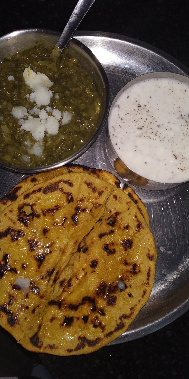 three different types of food on a metal plate with spoons and sauces next to each other