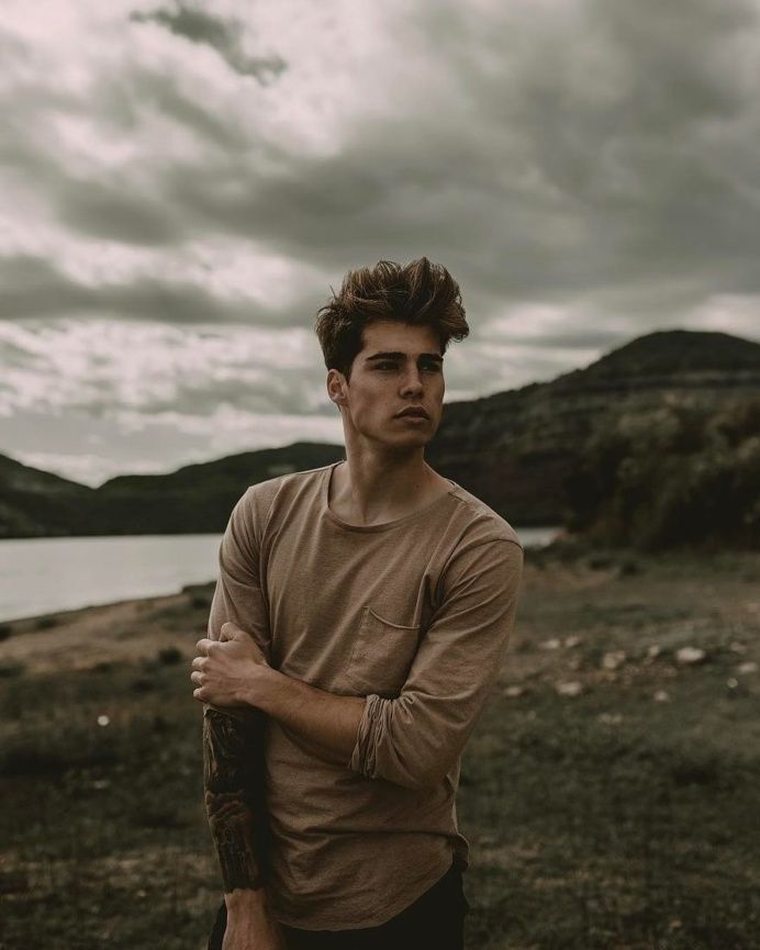 a man standing in front of a body of water with his arms crossed and looking at the camera