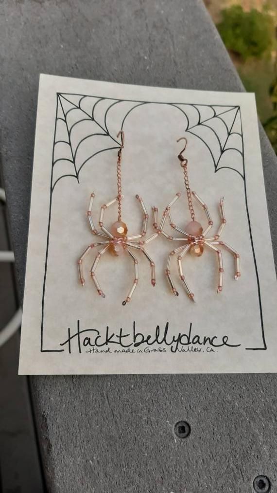 two spider earrings on top of a piece of paper with the words, harkt bell