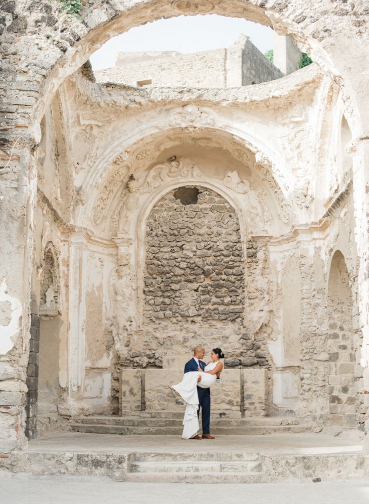 a bride and groom standing in front of an old building