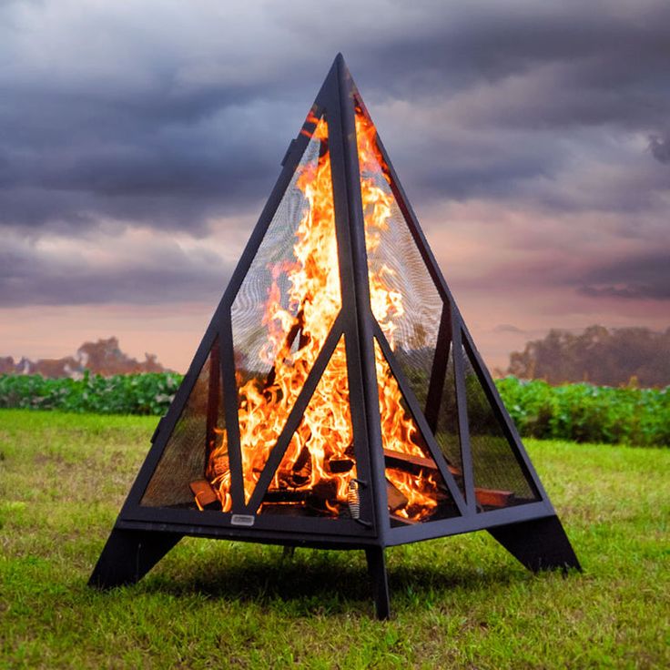 a fire pit in the middle of a field with dark clouds above it and grass on both sides