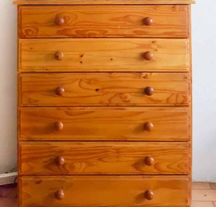 a wooden dresser sitting on top of a hard wood floor next to a white wall