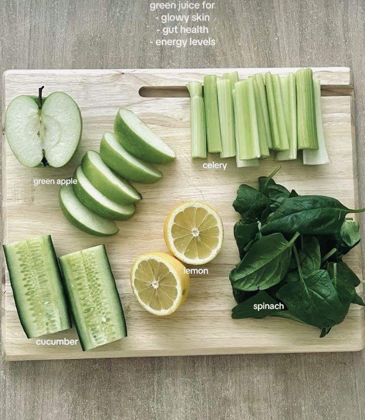 a cutting board topped with cucumbers, lemons and green apples