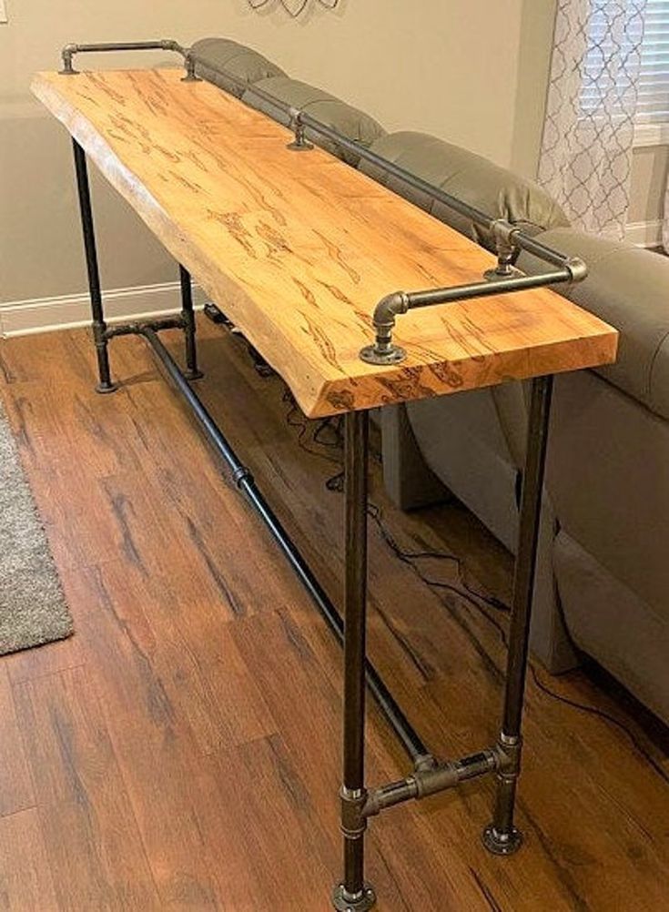 a wooden table sitting on top of a hard wood floor next to a gray couch