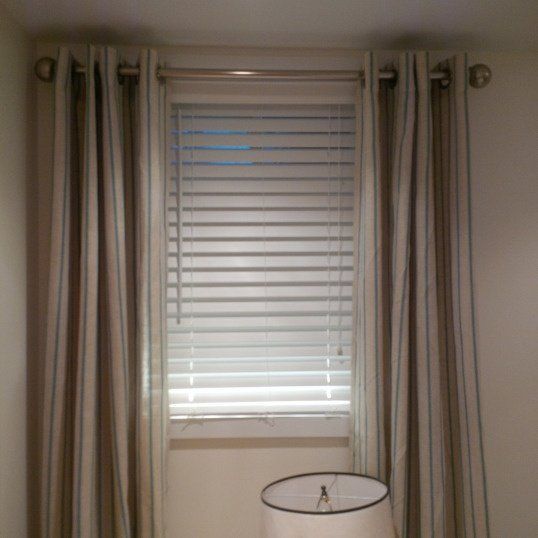 a lamp is sitting in front of a window with blinds on the windowsills