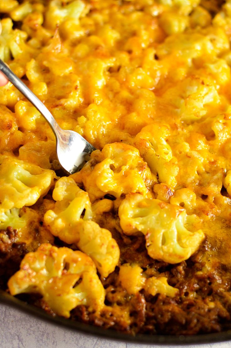 a close up of a spoon in a casserole dish with macaroni and cheese