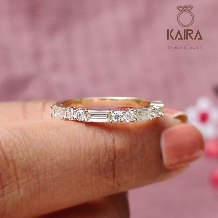 a woman's hand holding a gold ring with three baguettes on it