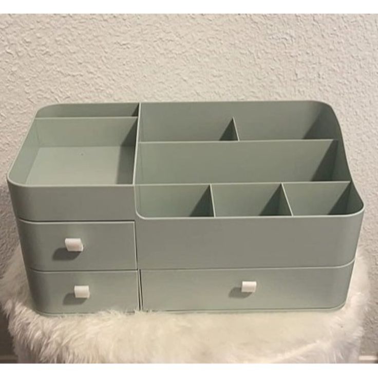 a gray drawer with six drawers on top of white furnishing and a wall in the background