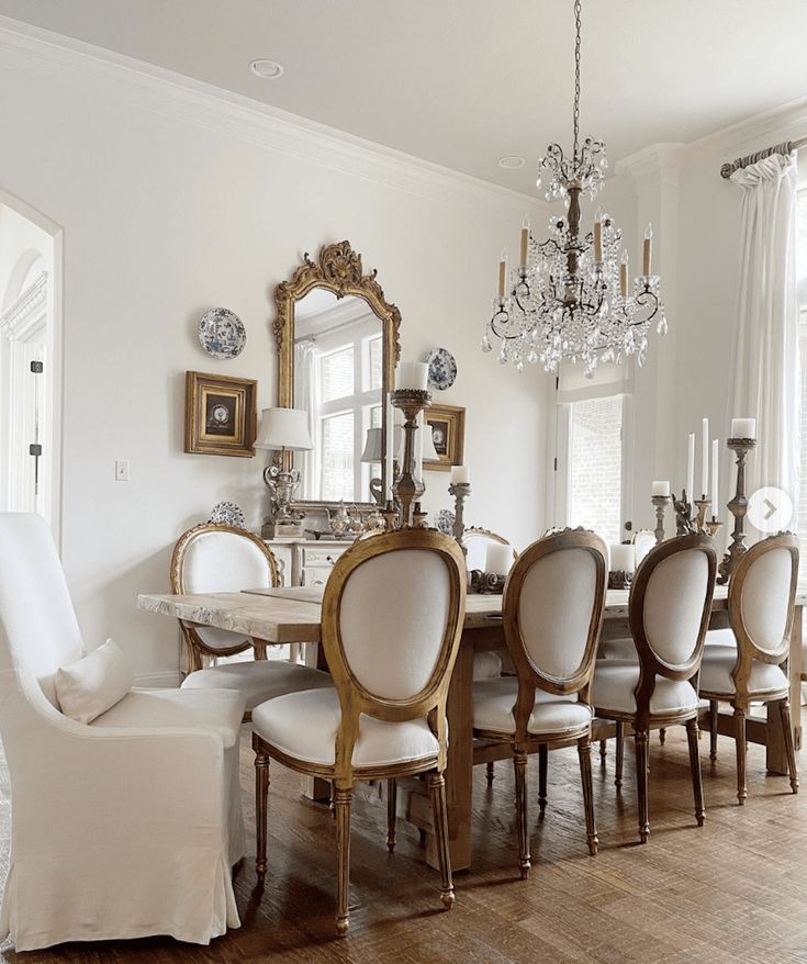 a dining room table with white chairs and chandelier