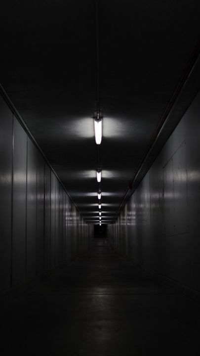 an empty dark tunnel with light at the end and no one in sight on the other side