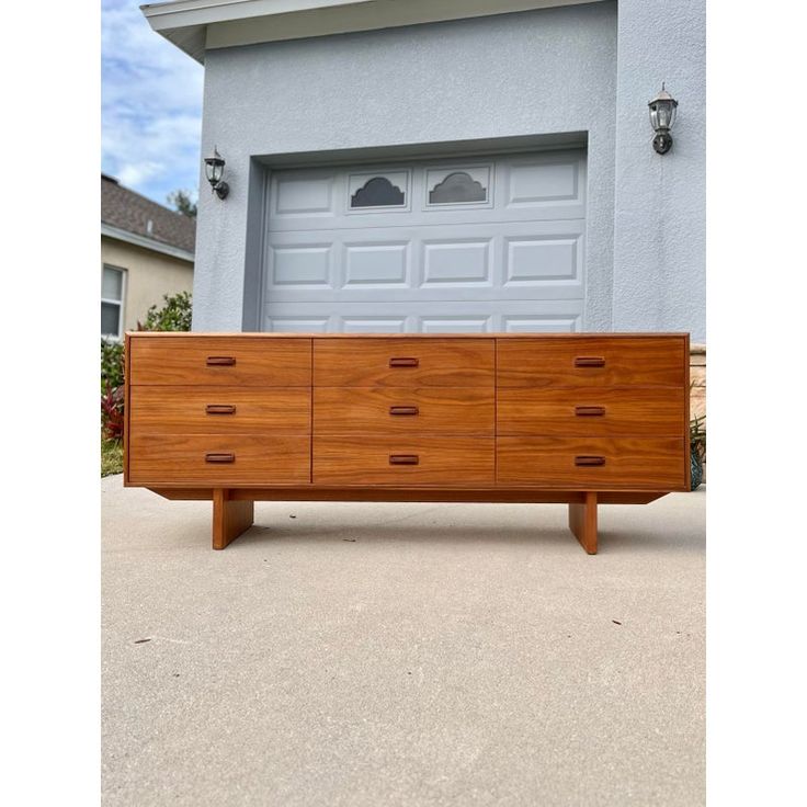 a large wooden dresser sitting in front of a garage door on the side of a house