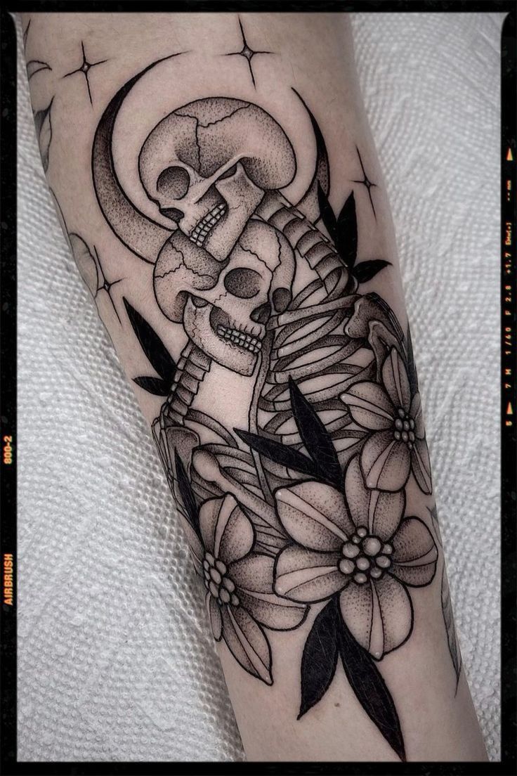 a black and white tattoo with a skull sitting on top of a flower in front of it