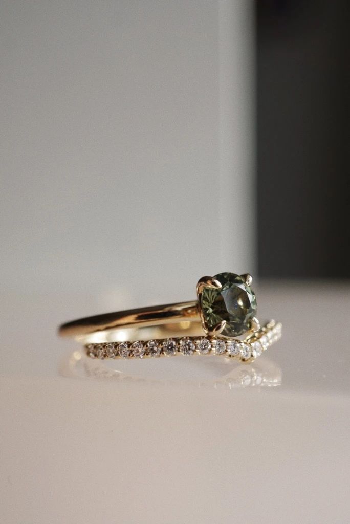 a close up of a ring on a table with a diamond and green stone in the middle