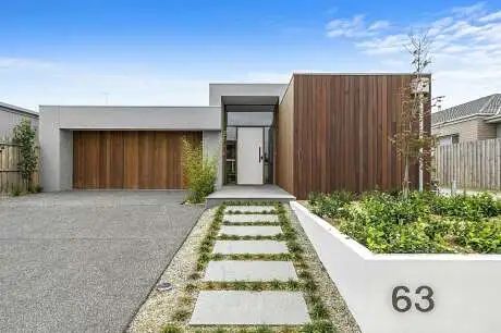 a modern house with landscaping in the foreground and a driveway leading up to it