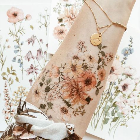 a close up of a person's arm with flowers on it and a gold disc