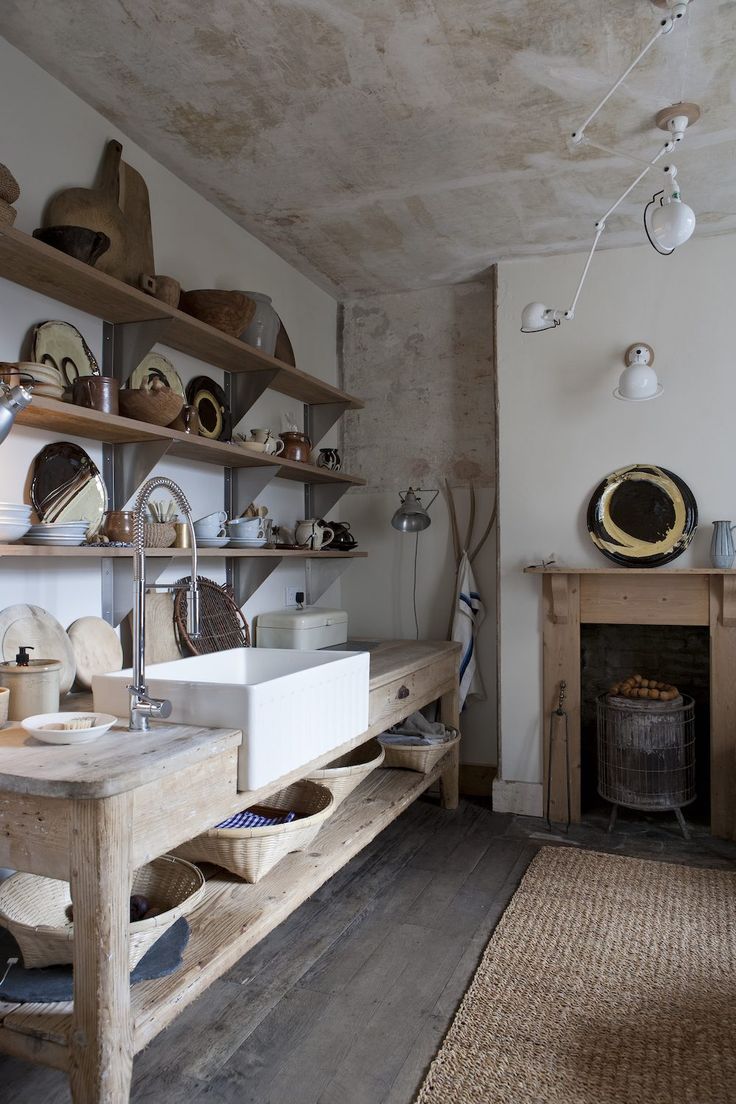 an old fashioned kitchen with wooden shelves and white sinks