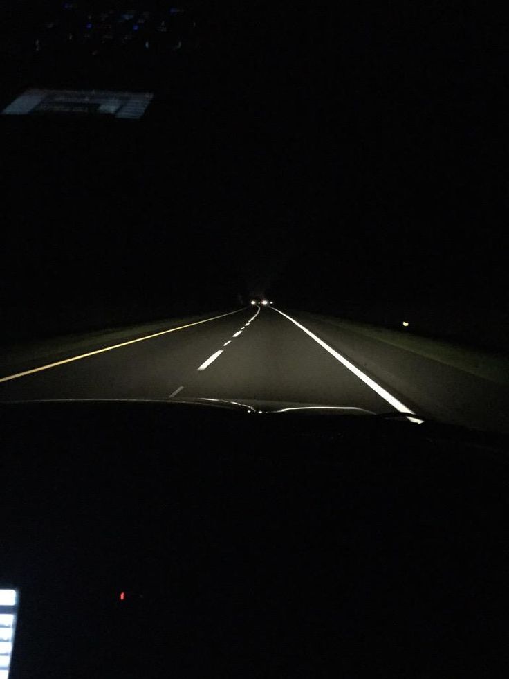 a car driving down a dark road at night