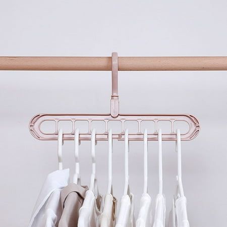 clothes hanging on a rail in front of a white wall and a wooden hanger