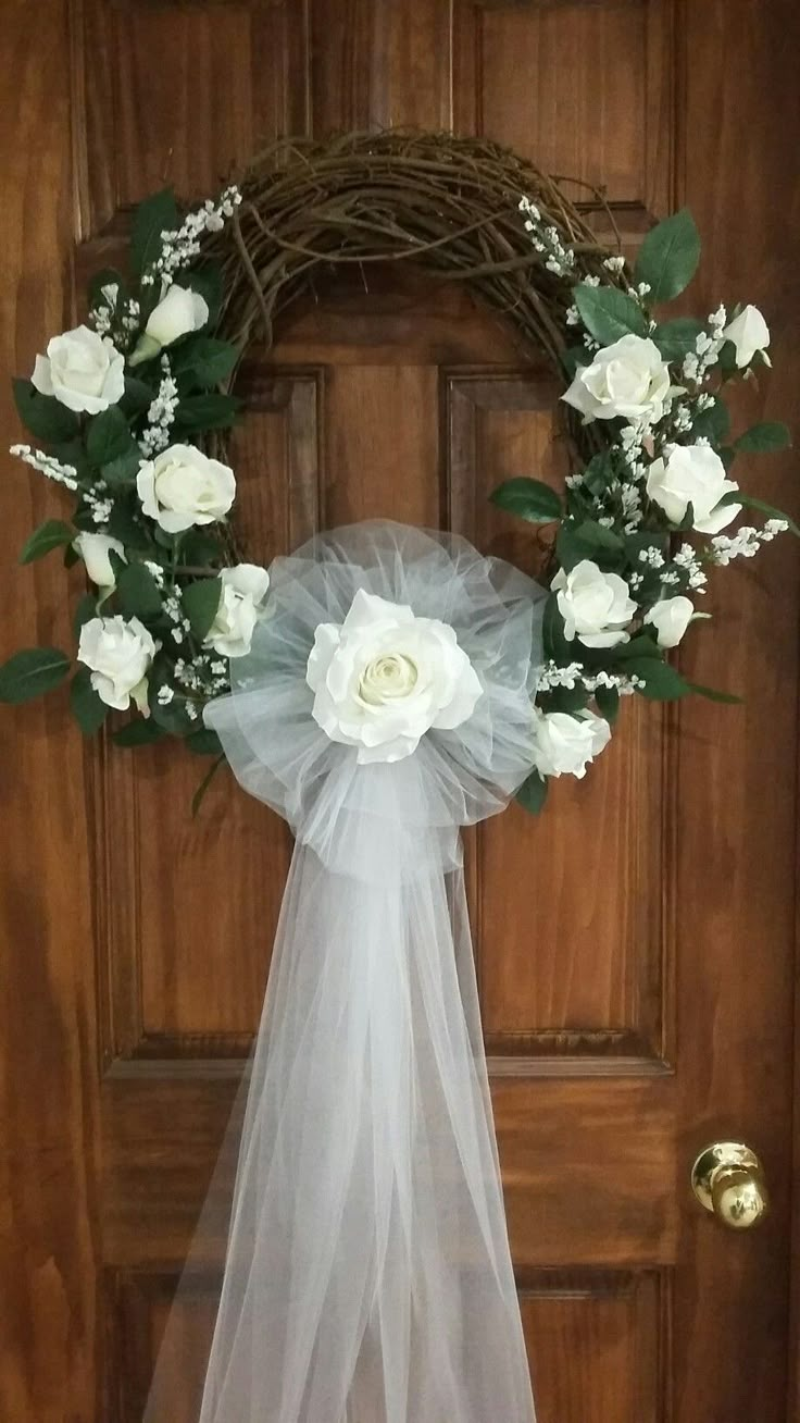 a wreath with white flowers and greenery on the front door