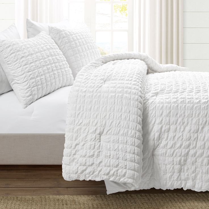 a bed with white comforter and two pillows