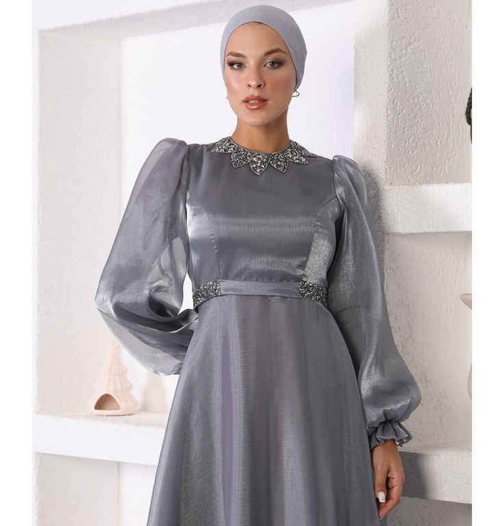 Modest Formal Satin Dress G531 Grey ATTENTION: This item has a special return policy, different from our regular store policy. See details below. A classy evening dress perfect for formal events! Features a gemmed petal design along the neckline, puffed sleeves, and is made with sleek satin. FEATURES: - Fully lined - Satin fabric with organza overlay - Gemmed petal design along neckline - Puffed sleeves with a small flare at the wrist - Matching satin waistband with glitter along sides FABRIC Satin fabric made from 100% Polyester. Weighs about 2 lbs CARE: Dry clean only Do not machine wash Do not machine dry Do not bleach Made in Turkey SPECIAL RETURN POLICY FOR EVENING GOWNS The following return policy applies on all evening gowns: • Return must be requested within 48 hours of receiving t Elegant Satin Gown With Sequins, Elegant A-line Sequin Gown, Elegant Evening Dress With Rhinestones And Fitted Bodice, Elegant Gown With Rhinestones For Prom Season, Elegant Sequined Prom Dress, Elegant Rhinestone Gown For Prom Season, Elegant Gown With Rhinestones For Banquet, Elegant Embellished Gala Dresses, Formal Evening Dress With Rhinestones And Fitted Bodice