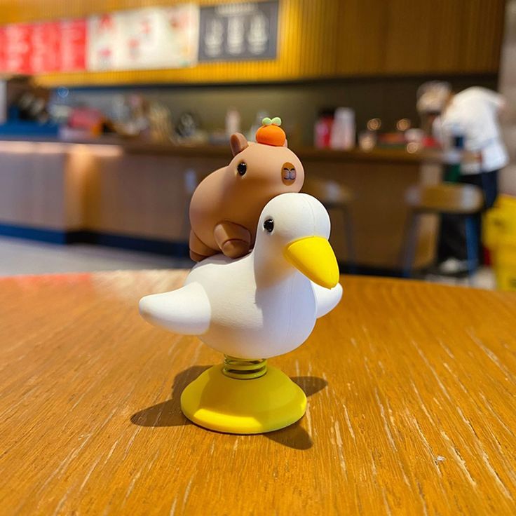 a small toy duck and horse on top of a wooden table in front of a counter