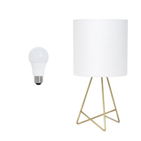 a lamp next to a white light bulb on a metal stand with a gold base