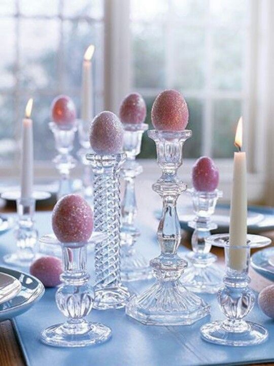 a table topped with lots of candles and glass vases filled with pink balls sitting on top of each other