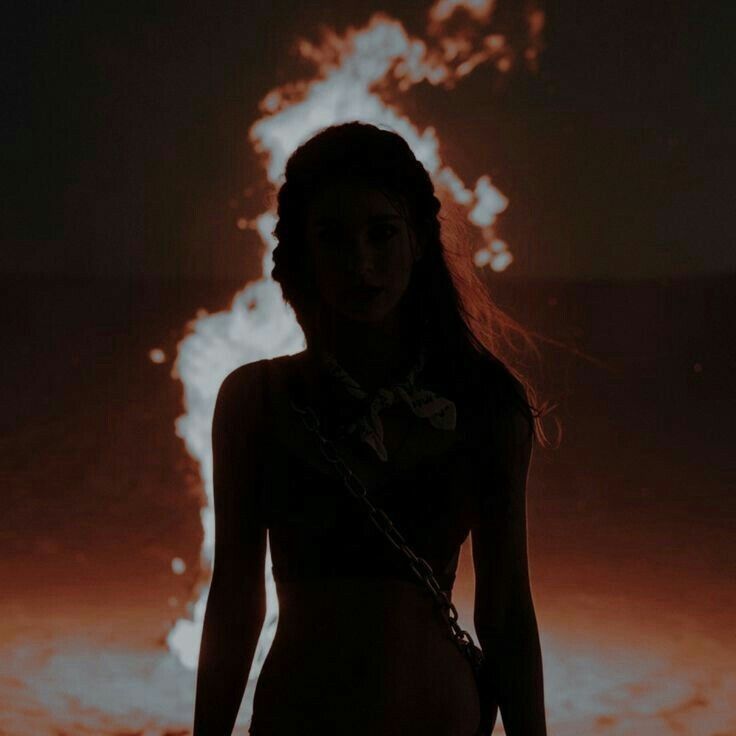 a woman standing in front of a fire with flames coming out of her chest and behind her