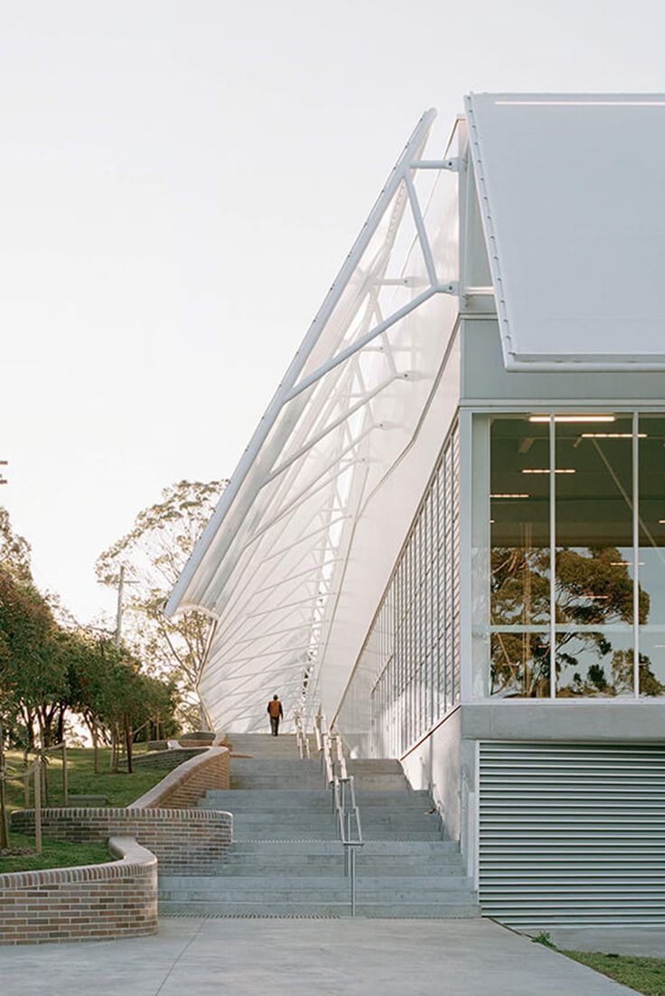 a person walking up some steps in front of a building with a large white roof