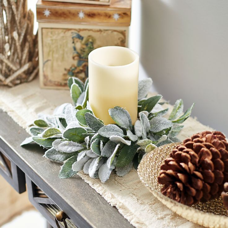 a candle and some pine cones are on a table next to other decorative items such as candlesticks