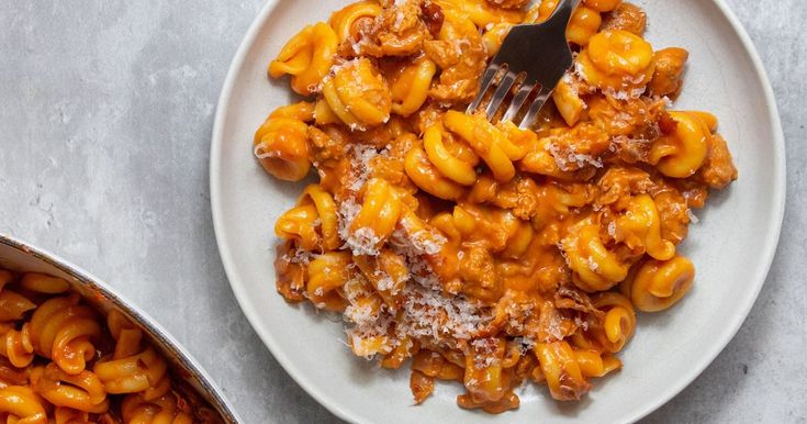 a white plate topped with macaroni and cheese next to a pot of sauce