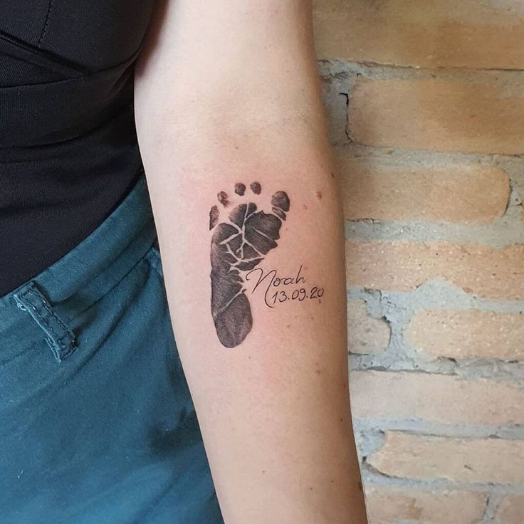 a woman with a tattoo on her arm that has a hand and foot print in the shape of a baby's footprints