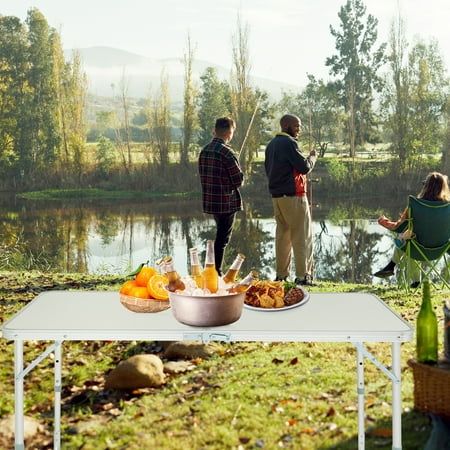 three people are standing near a table with food and drinks on it in front of a lake