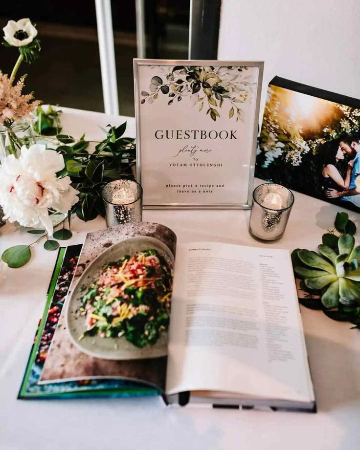 an open book sitting on top of a table next to some flowers and other items