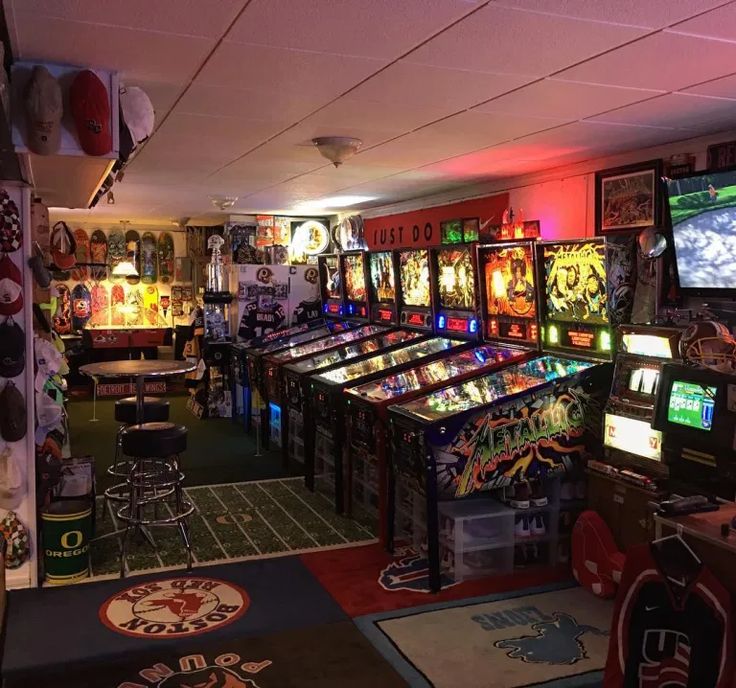 a room filled with lots of pinball machines and video game screens on the walls