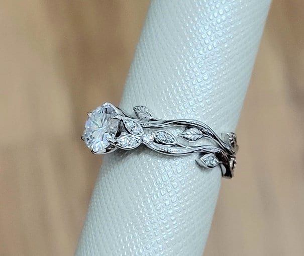 a diamond ring is sitting on top of a white napkin with a flower design in the middle