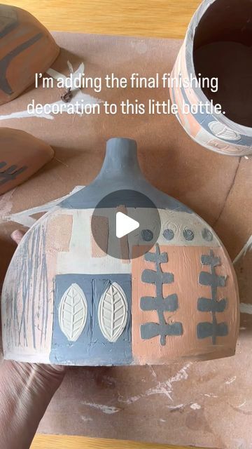 someone is making a clay pot out of paper machs and then painting it with the words i'm adding the final finishing decoration to this little bottle