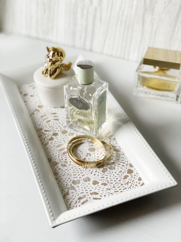 a white tray with two rings on it and a bottle of perfume next to it