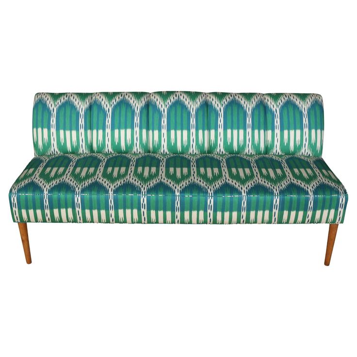 a green and white patterned couch with wooden legs