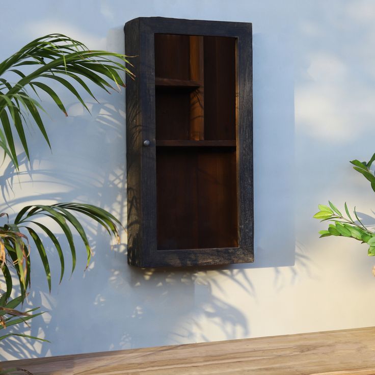 a wooden shelf sitting on the side of a wall next to a potted plant