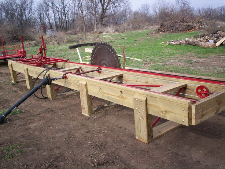 a wooden bench with two red wheels on it and a hose attached to the back