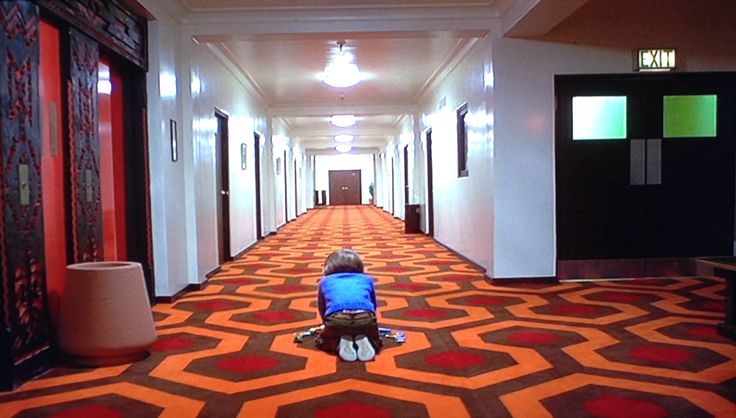 a child is sitting on the floor in an empty hallway with red and black walls