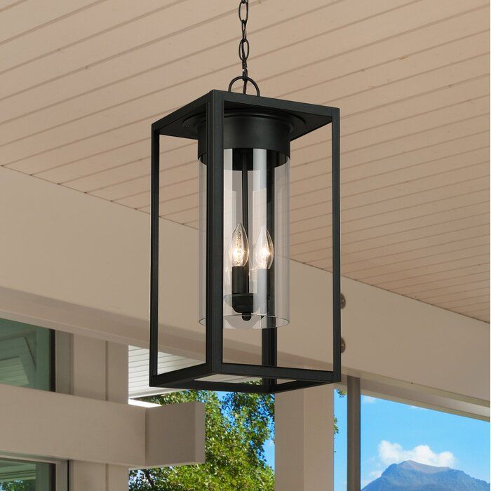 an outdoor hanging light with two lights on the ceiling and some trees in the background