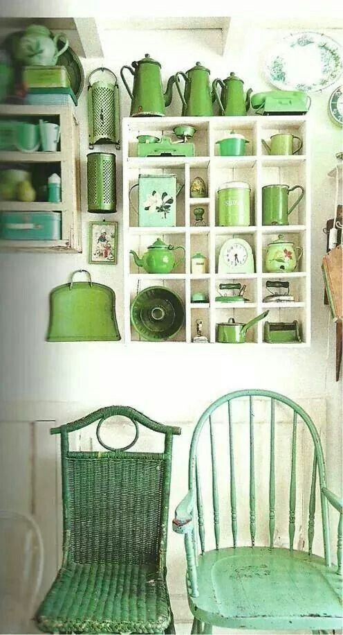 two green chairs sitting next to each other in front of a shelf filled with dishes